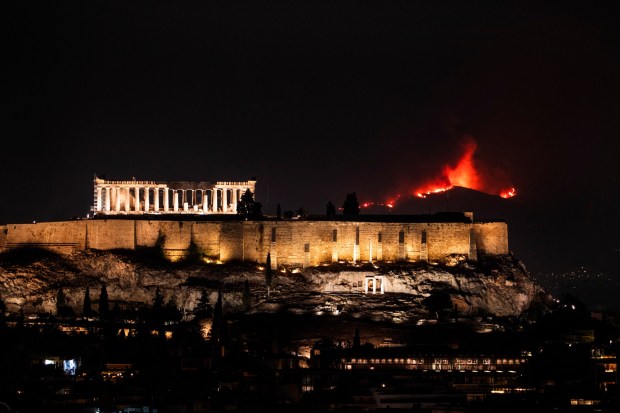 Flames from a wild fire are seen behind the Parthenon Temple atop the Acropolis hill, in Athens, on Aug. 23, 2023 (Photo by Andrea Bonetti / SOOC / SOOC via AFP) (Photo by ANDREA BONETTI/SOOC/AFP via Getty Images)