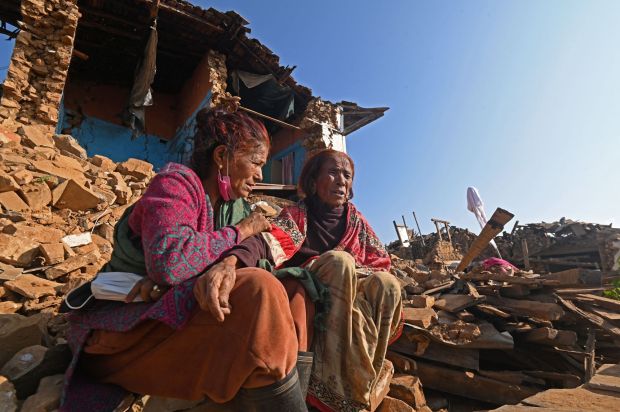 Survivors sit in front of their damaged house in Khalanga of Jajarkot district on November 6, 2023. At least 157 people were killed in isolated western districts of the Himalayan country when the 5.6-magnitude earthquake hit late November 3. (Photo by PRAKASH MATHEMA / AFP) (Photo by PRAKASH MATHEMA/AFP via Getty Images)