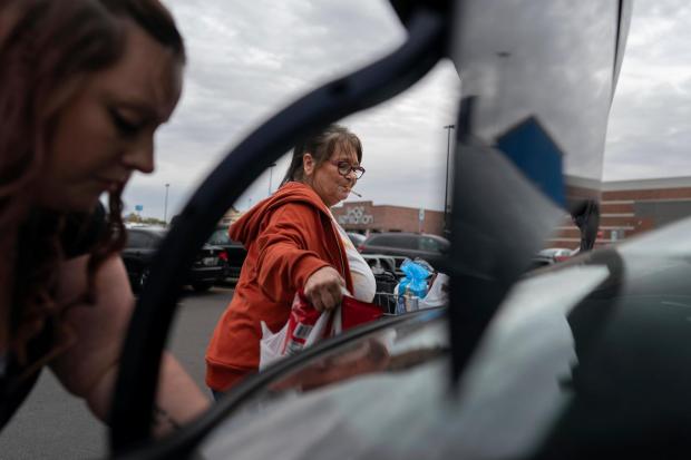 Jesse Johnson, left, of the Family Resource Center helps her client Jodi Ferdinandsen load groceries into the trunk at Walmart in Findlay, Ohio, Thursday, Oct. 12, 2023, before driving her home. Johnson said a peer support worker from the same organization was instrumental in helping her with her early recovery. (AP Photo/Carolyn Kaster)